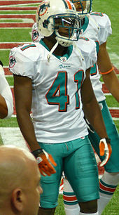 Photograph of a player wearing a helmet, with shoulder pads and thigh pads visible under their uniform