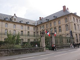 Entrée de la Bibliothèque Stanislas : grilles sur rue, bâtiment en "U" et cour intérieure paysagée.