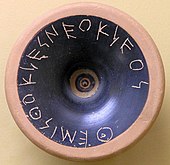 Pièce de céramique ronde avec une inscription en grec.
