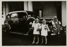 Two children standing next to a Plymouth with "AA 20" plate. The car belonged to the family of J.W. Bijleveld. c. 1936. Plymouth van de familie J.W. Bijleveld, kenteken AA20, Magelang, KITLV 26054.tiff