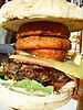 A steakburger with cheese and onion rings