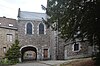 Kerk Notre-Dame d'el Vaux, keermuur, trottoir langs de zuidelijke gevel van de kerk, geplaveide steegjes, trappenpad onder de boog van het koor en het ensemble gevormd door het gebouw, trottoirs, steegjes en de square du Moustier (oude begraafplaats)