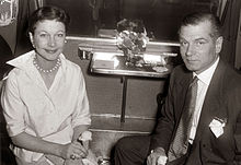 woman and man seated and looking towards camera