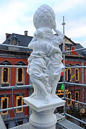 Sculpture neuve de marbre blanc montrant trois femmes adossées à un colonne surmontée d'une grosse pomme de pin