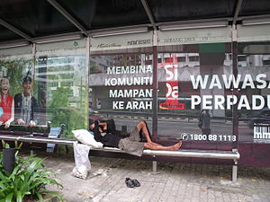 English: Homeless man sleeping at the bus stop...