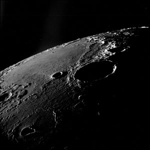 Oblique view facing southeast, from Apollo 11. The large crater right of center is Theophilus, and Mädler is to its left. Fracastorius is near the central horizon, and the white mountain on the horizon at right is part of the Rupes Altai. The teardrop-shaped crater in the lower left is Torricelli.