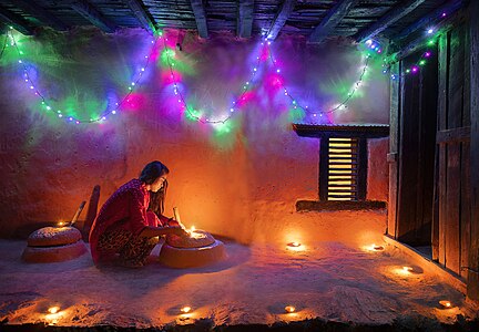 Woman lighting a diyo during Tihar, by Mithun Kunwar (edited by Radomianin)