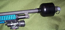A Mossberg 500 shotgun fitted with a grenade launcher adapter, shown holding a less lethal riot control grenade 500LCHR.jpg