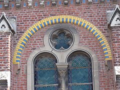 Un des arcs de plein-cintre de briques colorées, au dessus d'une fenêtre géminée.
