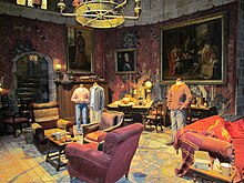 Une salle feutrée dans les tons rouges, remplie de gros fauteuils, de tapis, de tapisseries médiévales et de tableaux de peinture