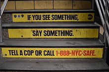 Stairs in the Times Square-42nd Street station with decals with the slogan, "If you see something, say something." If you see something, say something 42nd street subway.JPG
