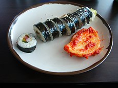 A sliced roll of Kimbap, with some kimchi.