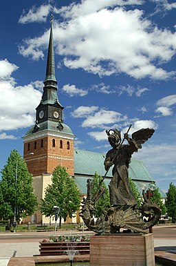 Mora kyrka, sedd från sydväst vid Mora gågata. I förgrunden syns statyn föreställande Sankt Mikael och draken.