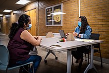 A school employee and parent in Des Moines, Iowa meet about school registration through plexiglass, July 2020 More Schools and Masks and COVID (50120211808).jpg