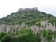 Ruins of the stone fortress of Mistra on a hilltop and of a stone wall below