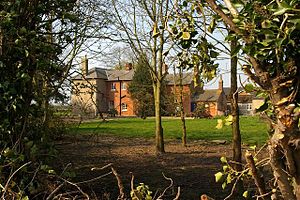 Large red-brick farmhouse, seen through trees