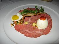 A unique version of steak and eggs with carpaccio beef, quail egg, deviled egg and vegetable salpicon