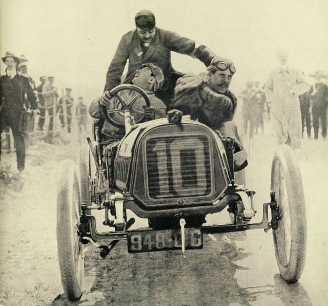 Photo de face d'une voiture avec trois personnes à bord.