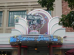 A photograph of a marquee reading "Where Famous Stars Dine" in blue over a doorway labelled 424 all under mock street signs, one reading "HOLLYWOOD" and the other reading "& VINE"