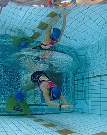 Underwater view of an underwater swimmer launching off the end of a pool.