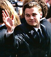 Leonardo DiCaprio is rising his hand.