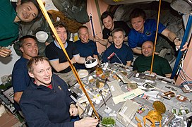 Neuf astronautes et cosmonautes autour de la table pour un repas à bord de la Station spatiale internationale.