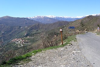 Blick ins Imperotal. Im Hintergrund das Dorf Cesio und die schneebedeckten Berge des Piemont