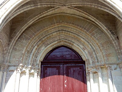 Porte rouge surmontée de volutes et d'une croisée d'ogives.