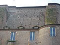 Photo couleur montrant un mur en brique avec l'empreinte de voûtes démolies surmontant la toiture d'une aile de château.