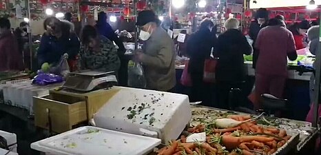 Residents of Wuhan wearing masks rushed out to nearby markets to buy vegetables and other food on 23 January during the outbreak