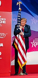 Trump relies on theatrical devices to market his messages, including animated gestures, pantomiming and facial expressions. Photo is from the 2019 Conservative Political Action Conference. President Donald J. Trump embraces the American flag at CPAC 2019.jpg