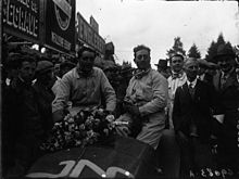 Photo de deux hommes, Benoist et Marinoni assis sur la carrosserie d'une voiture.