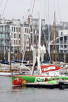 Vu de trois quarts avant, voilier vert et blanc amarré au ponton.