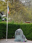 Plaque sur un rocher et mât portant un drapeau français.