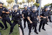 American Beverly Hills Police Department officers in light riot gear, consisting of just riot helmets and batons, during a Trump 2020 rally in 2019 BHPD riot cops, 2019.jpg