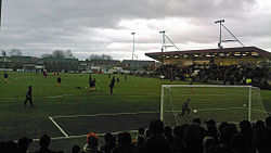 Photograph of players on a football pitch taken from a spectator stand.
