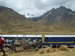 The train "The Andean" at La Raya Station with market stalls and the mountain Chimpulla in the background, Layo District-Santa Rosa District