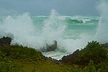 Sea spray fills the air amid high waves breaking on rocky coastline
