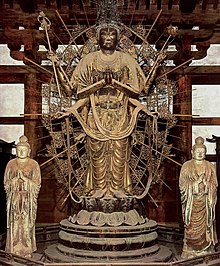 Statue de Fuku-kensaku Kannon, au centre, sur un haut piédestal, entouré de rayons dorés. Deux statues blanches sereines de par et d’autre, de taille deux fois moindre: les devas.