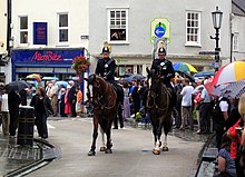 Des policiers à cheval déambulent parmi des gens.