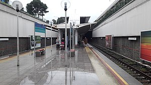 Bornova station platforms depicted with its island platforms. Several advertising boards are visible on the sides.