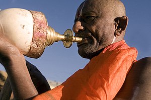 A Hindu priest blowing his conch during a puja...