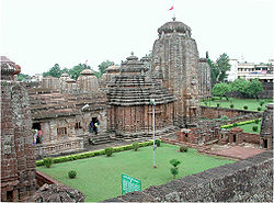 A group of temples made in laterite with a lawn in foreground