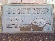 Typical signage embedded in pavement next to a storm drain in Boston, in the United States BosHarbor DrainWan.jpg