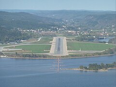 Foto einer Flughafen-Landebahn, im Vordergrund ein Gewässer