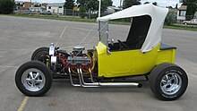 Convertible T-bucket in a hybrid style: traditional sidepipes and dropped tube axle, transverse front leaf spring, and non-traditional front disc brakes and five-spokes. T-bucket.jpg