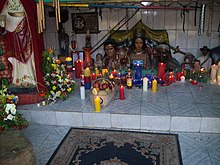 Household altar with idols of various Venezuelan figures and candles in red, yellow, white, and blue.