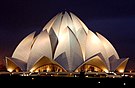 A large building with a lotus-shaped roof, lit up in front of a night sky.