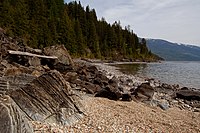 A rocky beach leading to a tree-covered shore along an inlet