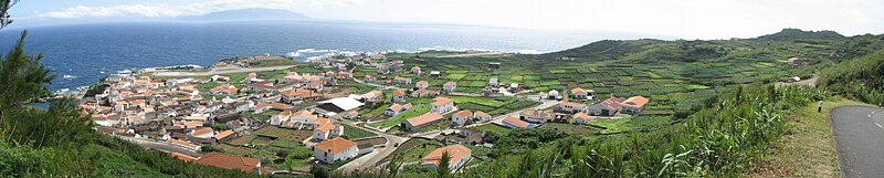 Vila do Corvo, a única povoação da ilha do Corvo, vista do miradouro. No horizonte avista-se a ilha das Flores.
